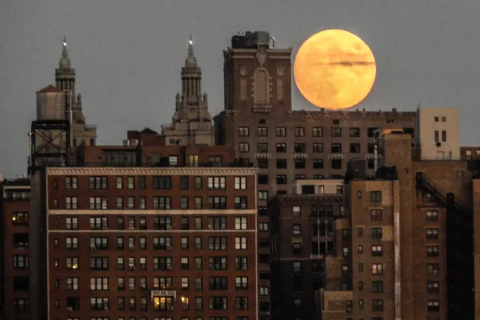A photo of a full yellow-tinted moon over Manhattan